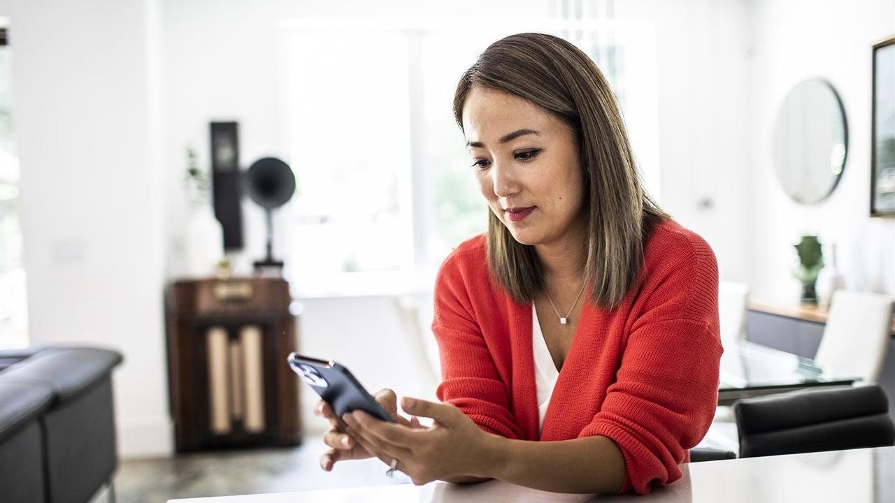 Woman using a phone app at home. With the Sydney Health app, members can find in-network care, see estimated costs and manage benefits in one place.
