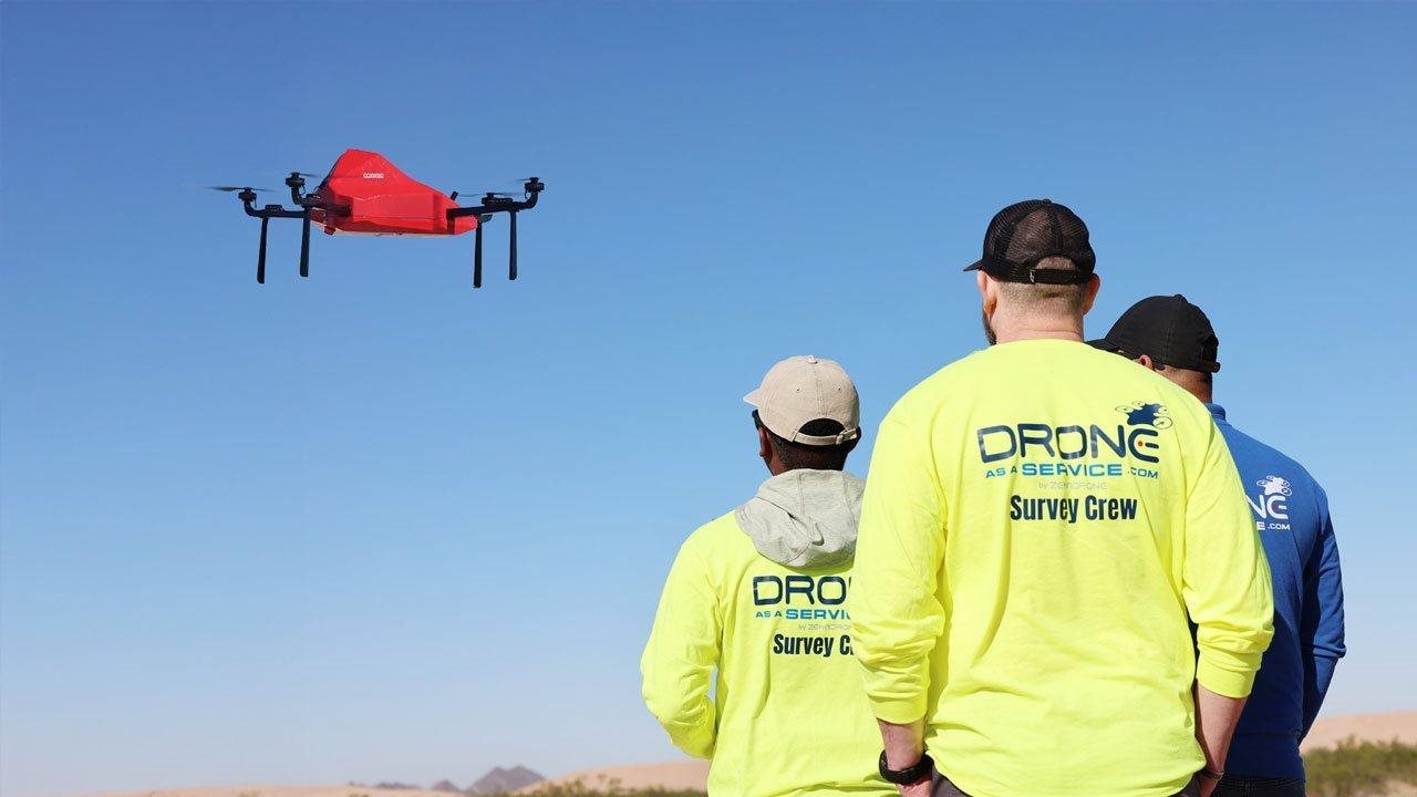 Drone as a service survey crew watching drone in the sky.