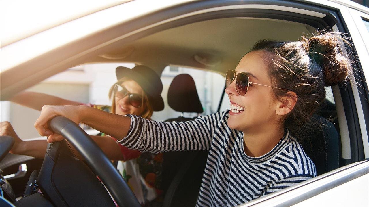 Two young women having fun driving a car. Flexcar is a new leasing opportunity providing month-to-month access to a car.