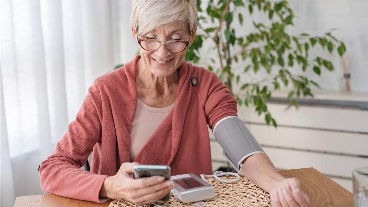 Senior woman takes blood pressure and uses phone app. Anthem Whole Health connects individual’s healthcare touchpoints.