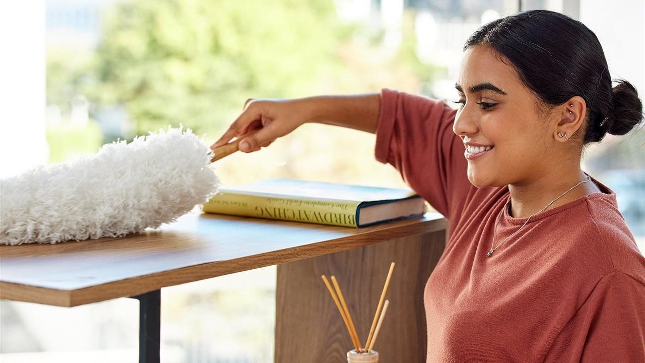 Woman using a duster to clean home. Thriftbooks has Spring cleaning tips.