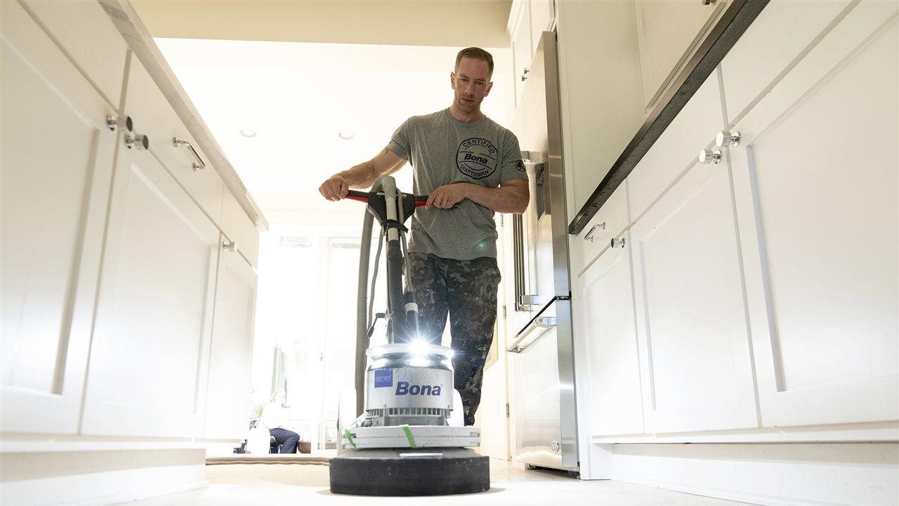 Man refinishing a hardwood floor. A Bona Certified Craftsman ensures your floor will be properly refinished.