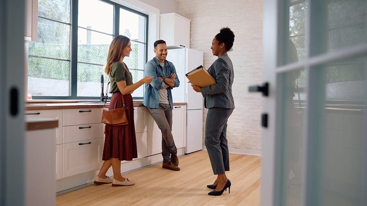 Couple talking with real estate agent while viewing the kitchen in a home.