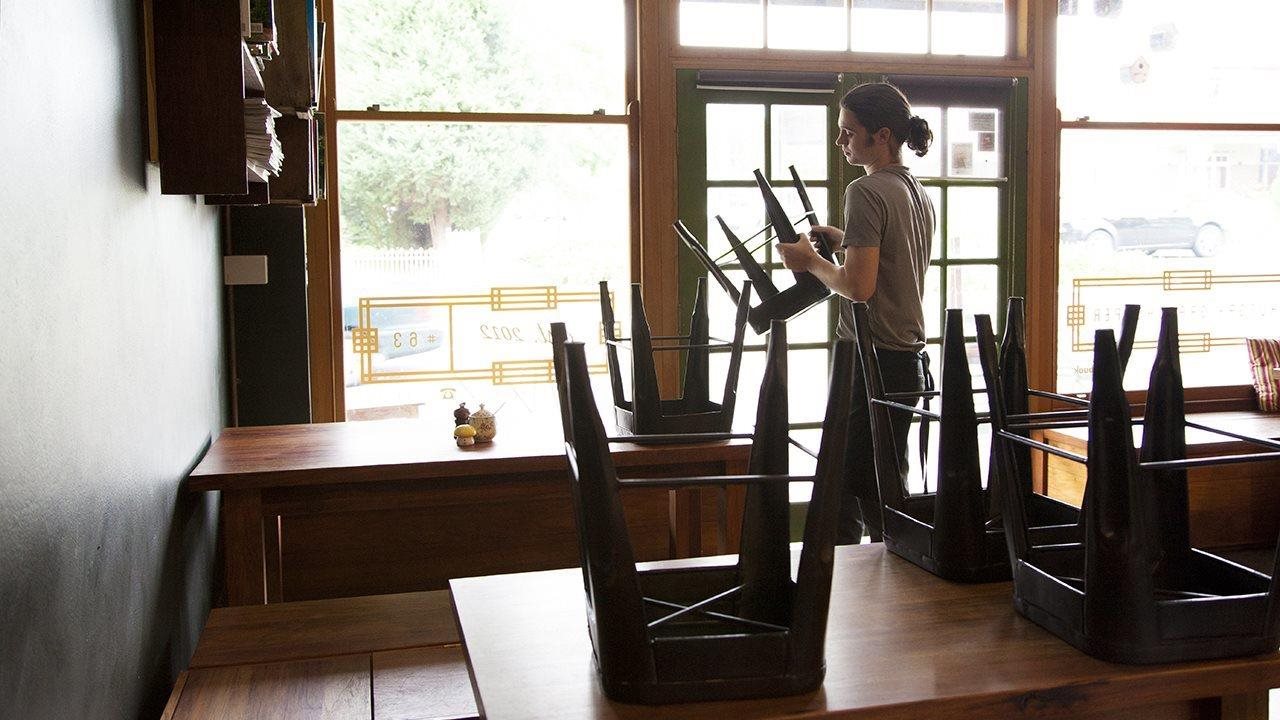 Young man stacking chairs in a restaurant.