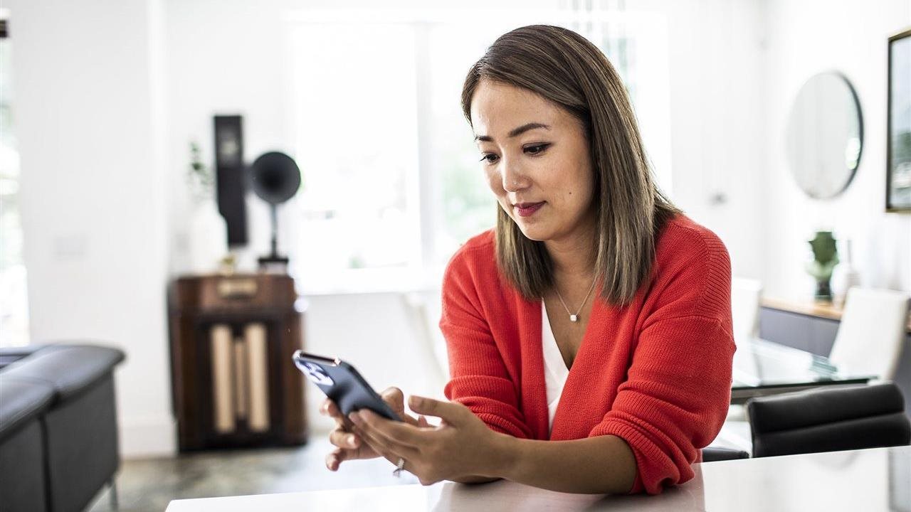 Woman using a phone app at home. With the Sydney Health app, members can find in-network care, see estimated costs and manage benefits in one place.