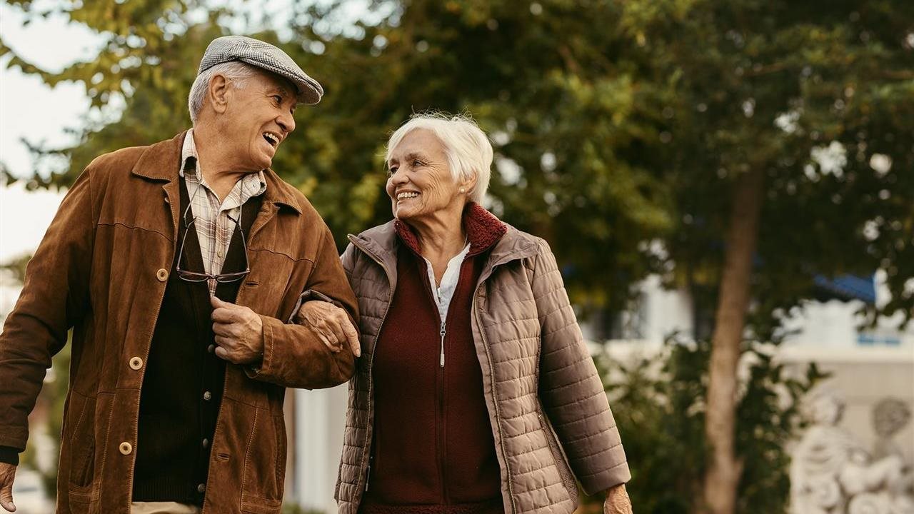 Senior couple in winter clothing walking in a park.
