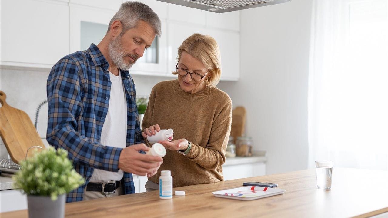 Senior couple in kitchen measuring out medications. BioPlusRX is a specialized pharmacy.