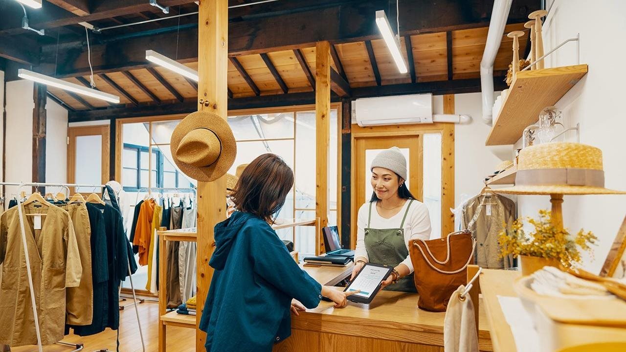 A cashier offers a customer her tablet to complete a payment.