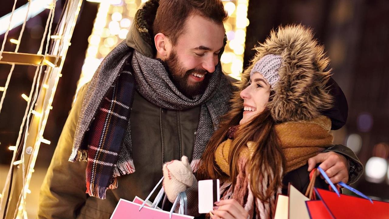 Happy couple bundled up for winter weather doing holiday shopping with their Platinum X5 Visa Signature® card which offers up to 5% cash back rewards on everyday purchases.