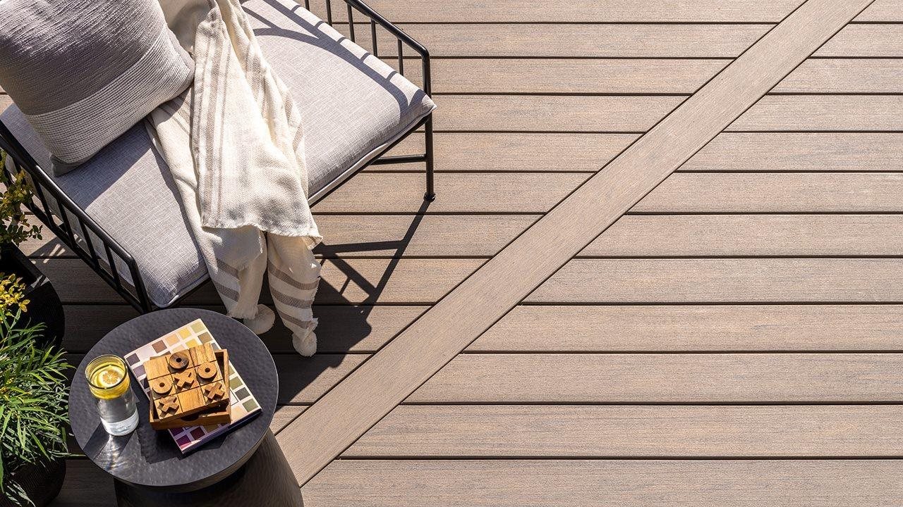 A chair and end table with a drink and tic-tac-toe board, on a composite patio.