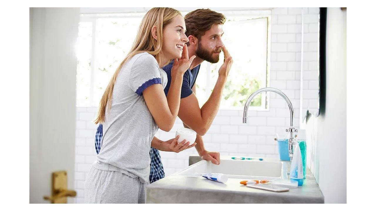 Couple washing their faces at the sink. The Panasonic Whisper Cozy Heater/Fan Combo removes excess humidity while heating the bathroom.