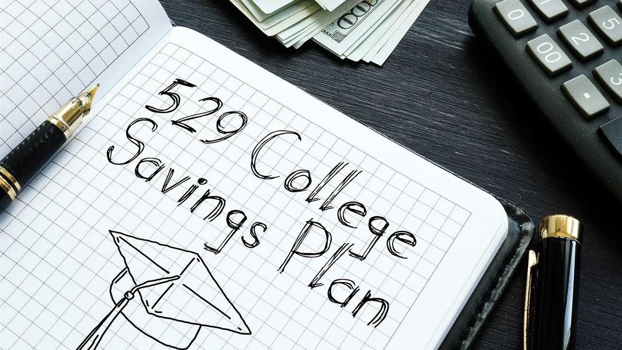 An open gridded journal with "529 College Savings Plan" written inside. Beneath it is a sketch of a graduation cap.