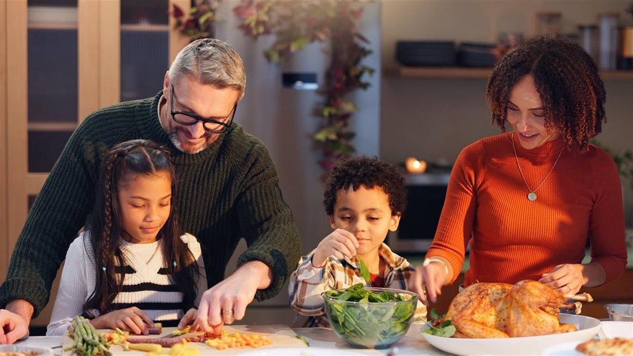 Diverse family of four prepping a holiday meal together in the kitchen.