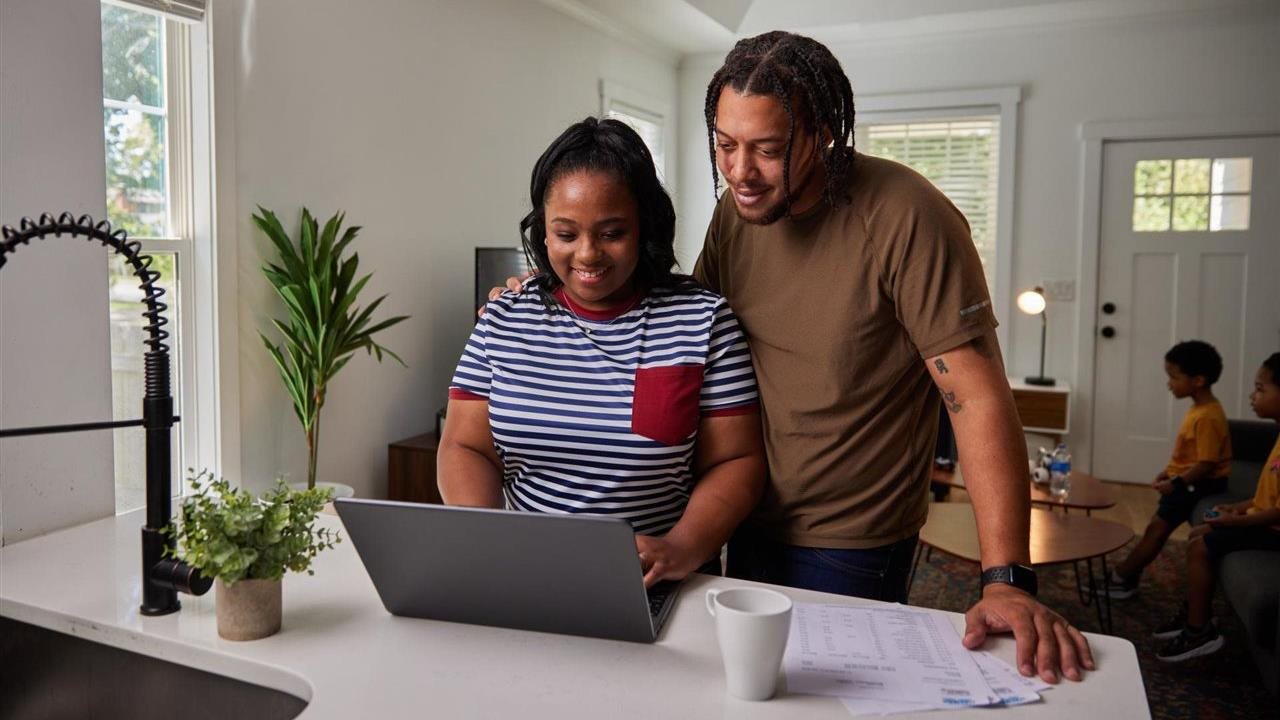 Couple standing at kitchen counter with laptop. TurboTax has a Free Edition.