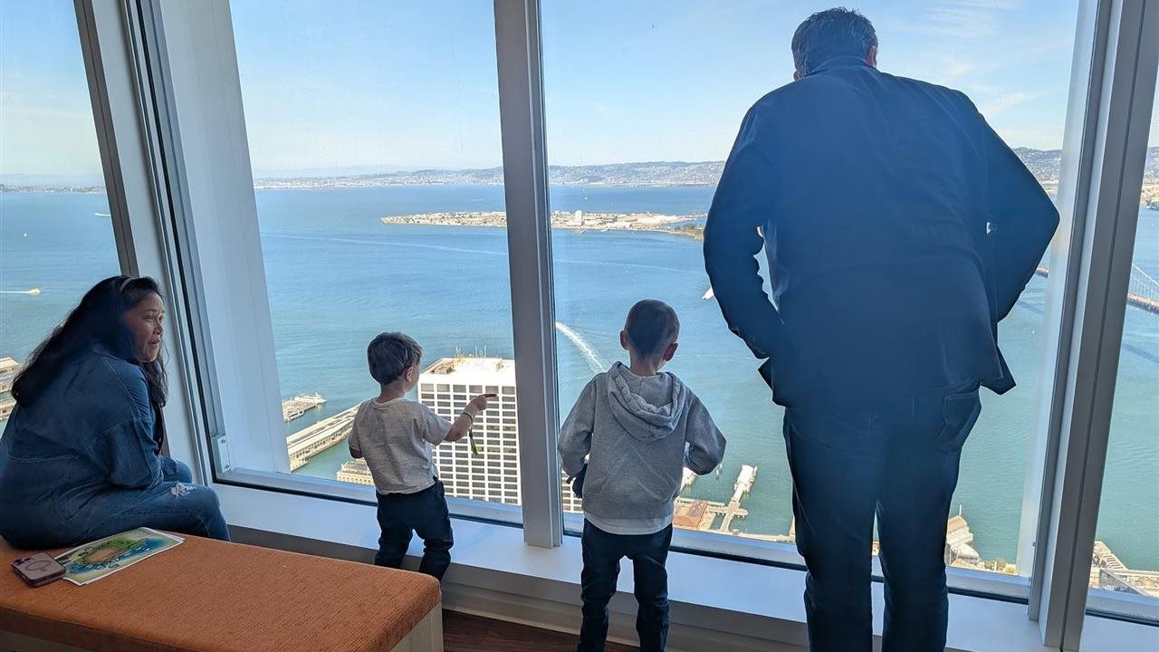 Make-A-Wish kid, Sam, and family at Salesforce’s San Francisco office enjoy sighting famous landmarks through a window.
