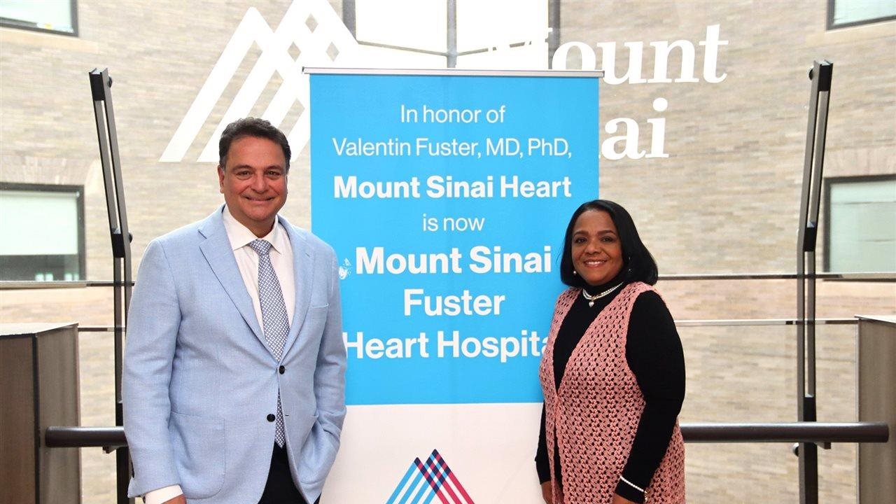 Two health care professionals standing in front of a sign that says “In honor of Valentin Fuster, MD, PhD, Mount Sinai Heart is now Mount Sinai Fuster Heart Hospital”