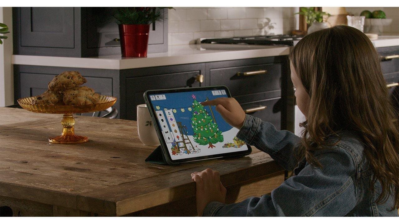 Child on a tablet at kitchen counter interacting with the Peanuts digital advent calendar 2025 from American Greetings.