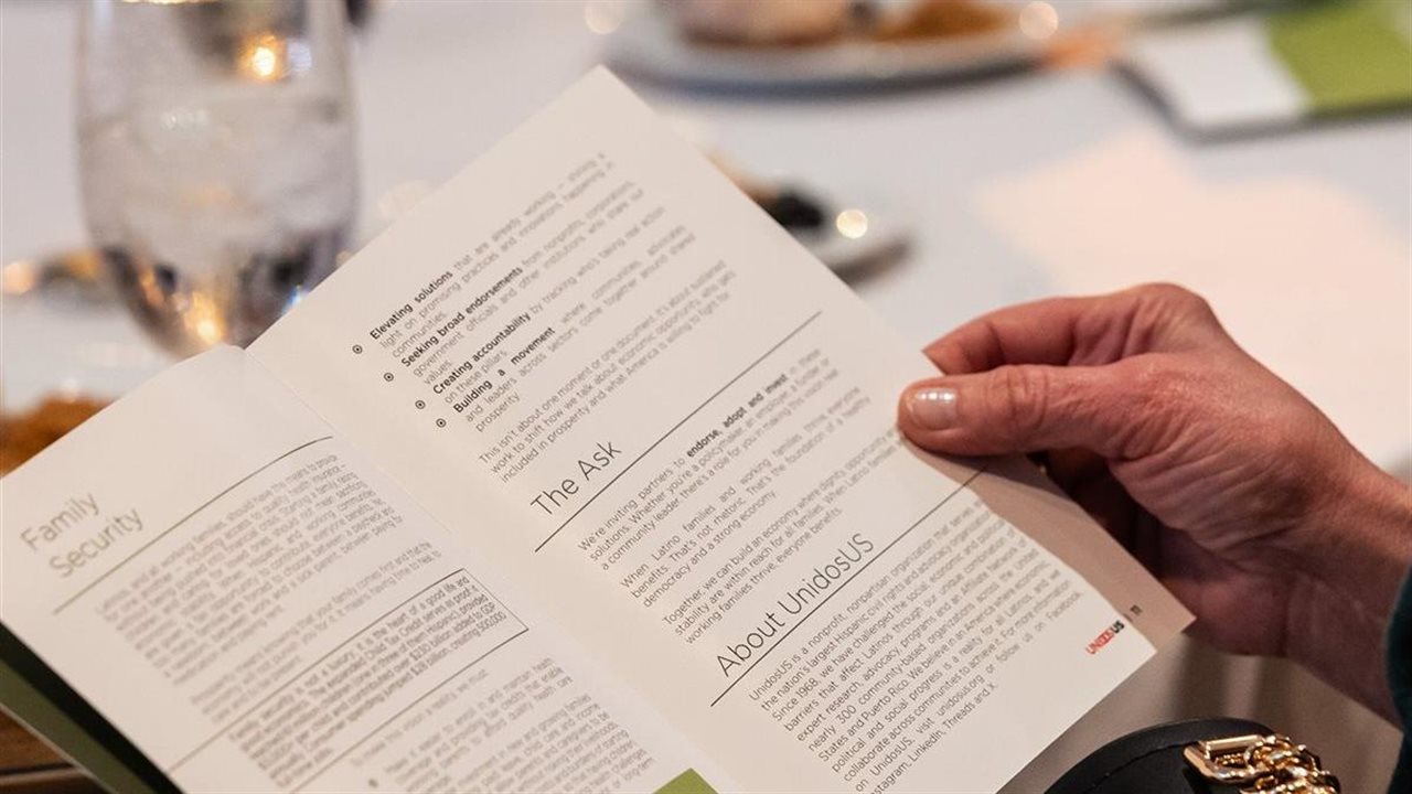 Mujer leyendo un folleto que habla de Unidos mientras cena en un hermoso restaurante.