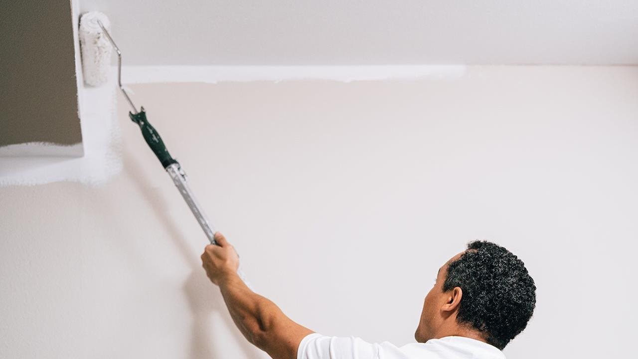 Representative from Five Star Painting using a roller to paint a room interior.