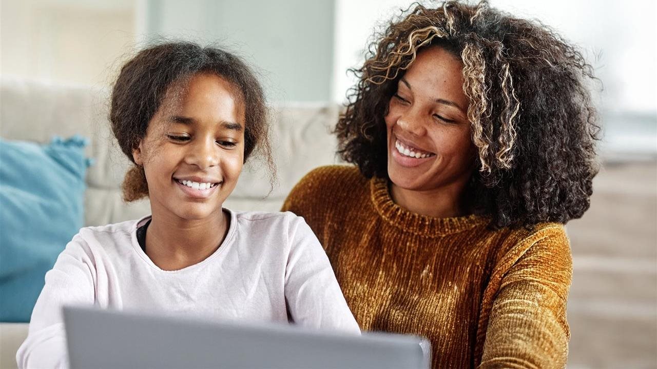 Mom and daughter working together on laptop. Navy Federal Credit Union has investment services available.