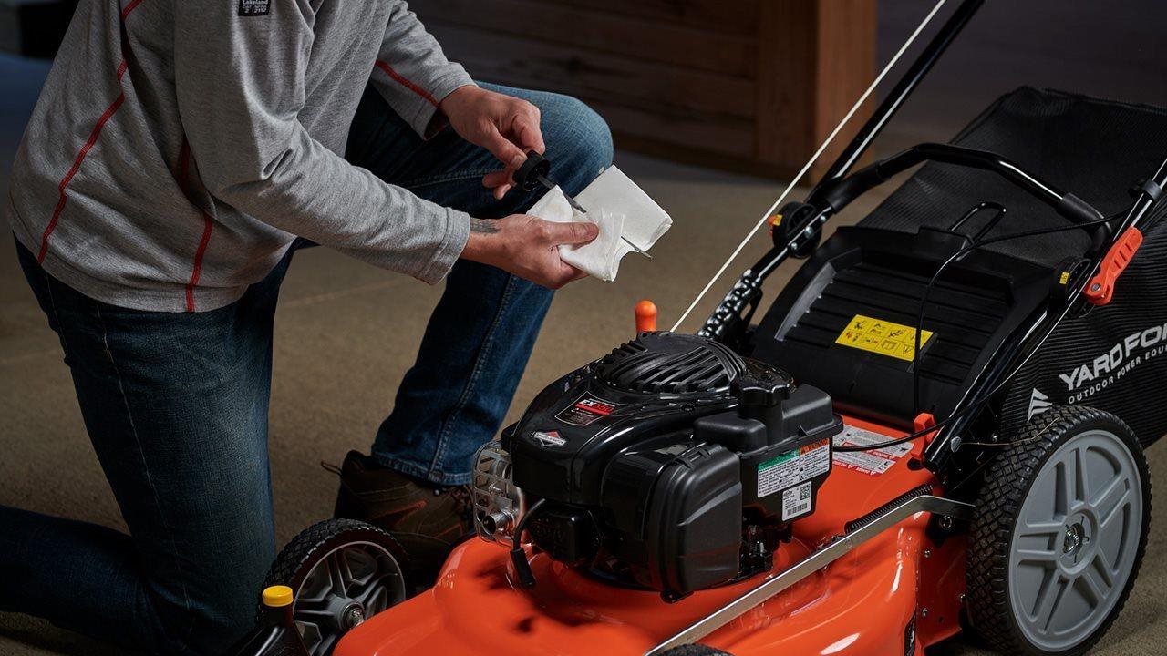 Man checking the oil in a gas powered mower. Gas-powered lawn mowers from Briggs & Stratton are durable.