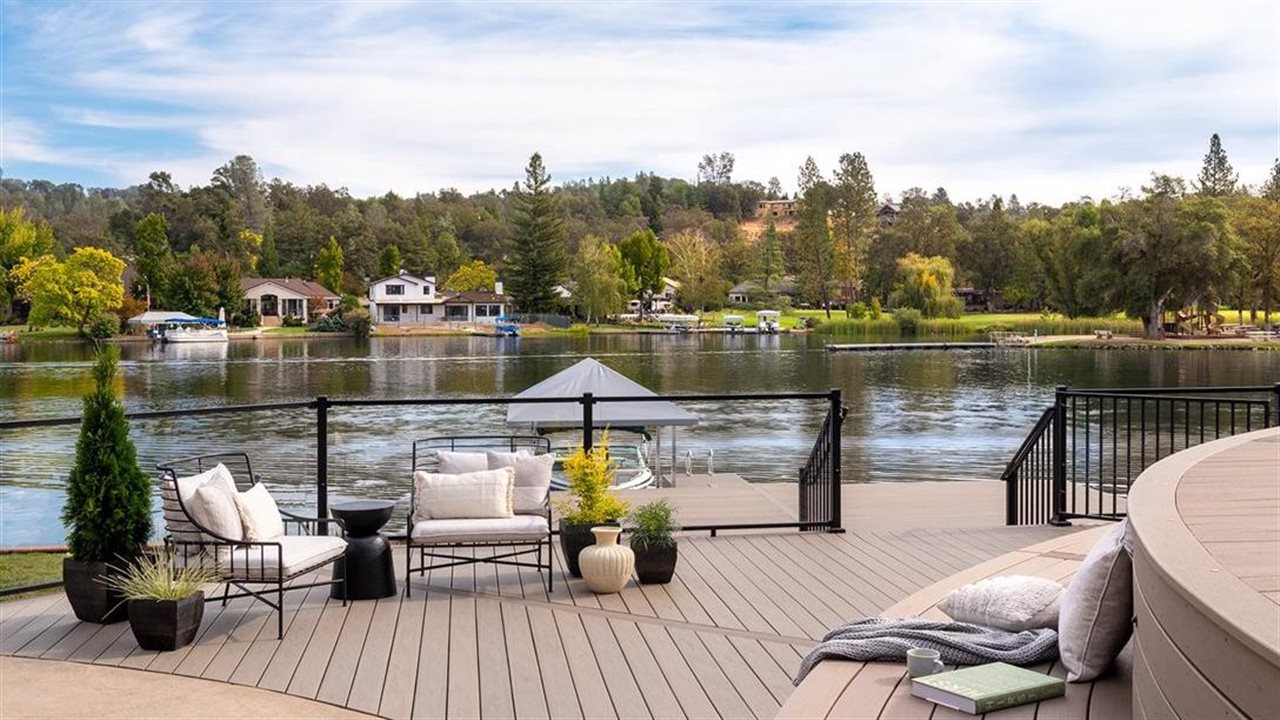 A view of a serene lake from wooden decking and railing.