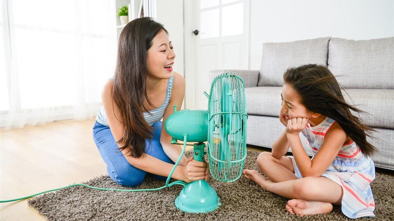 Mom setting up a fan for her daughter in the living room. Stay cool and save with energy-smart solutions at OnCourse.com.