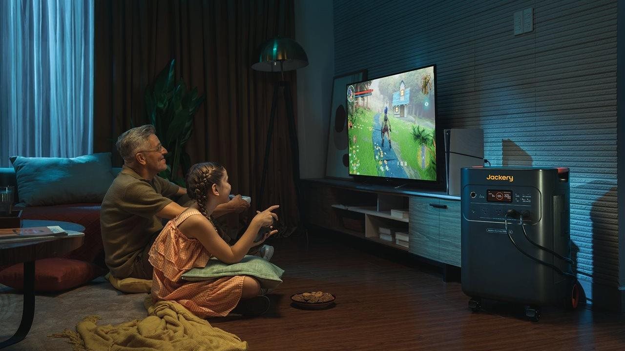 Grandfather and granddaughter playing video game on screen powered by Jackery Home Power Backup.