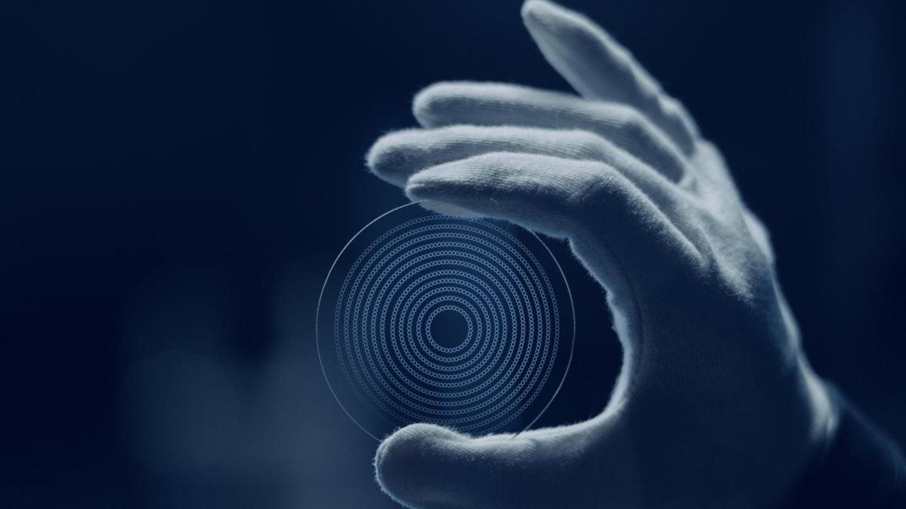 Gloved hand holding EssilorLuxottica's Stellest Lens.