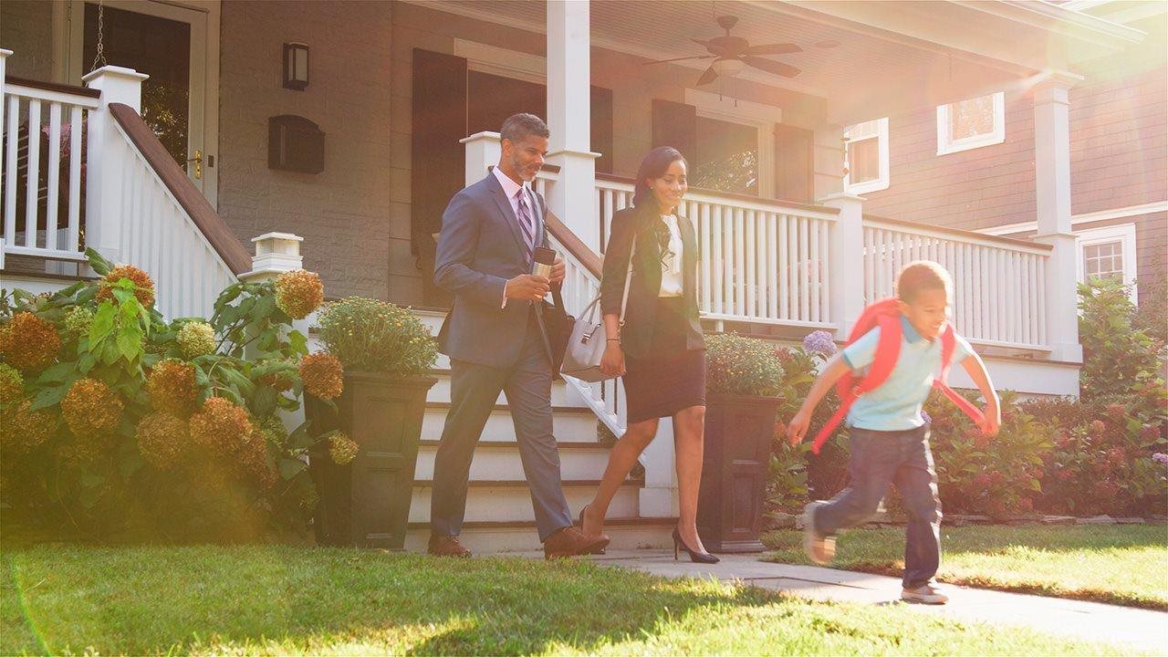 Business couple leaving the house in the morning with their elementary school child.