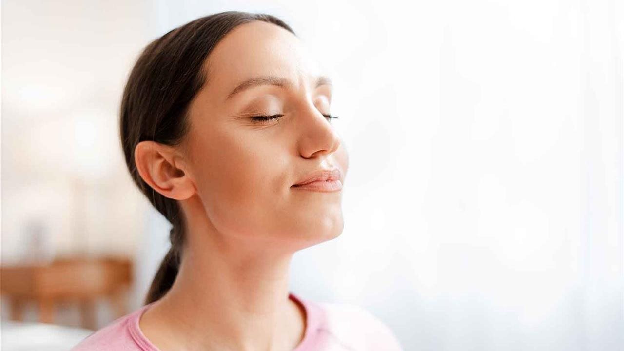 Woman with her eyes closed taking a deep breath having been relieved of her allergy & asthma symptoms.