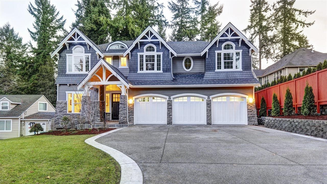 Luxury house with three-car garage, concrete driveway and blue vinyl siding.