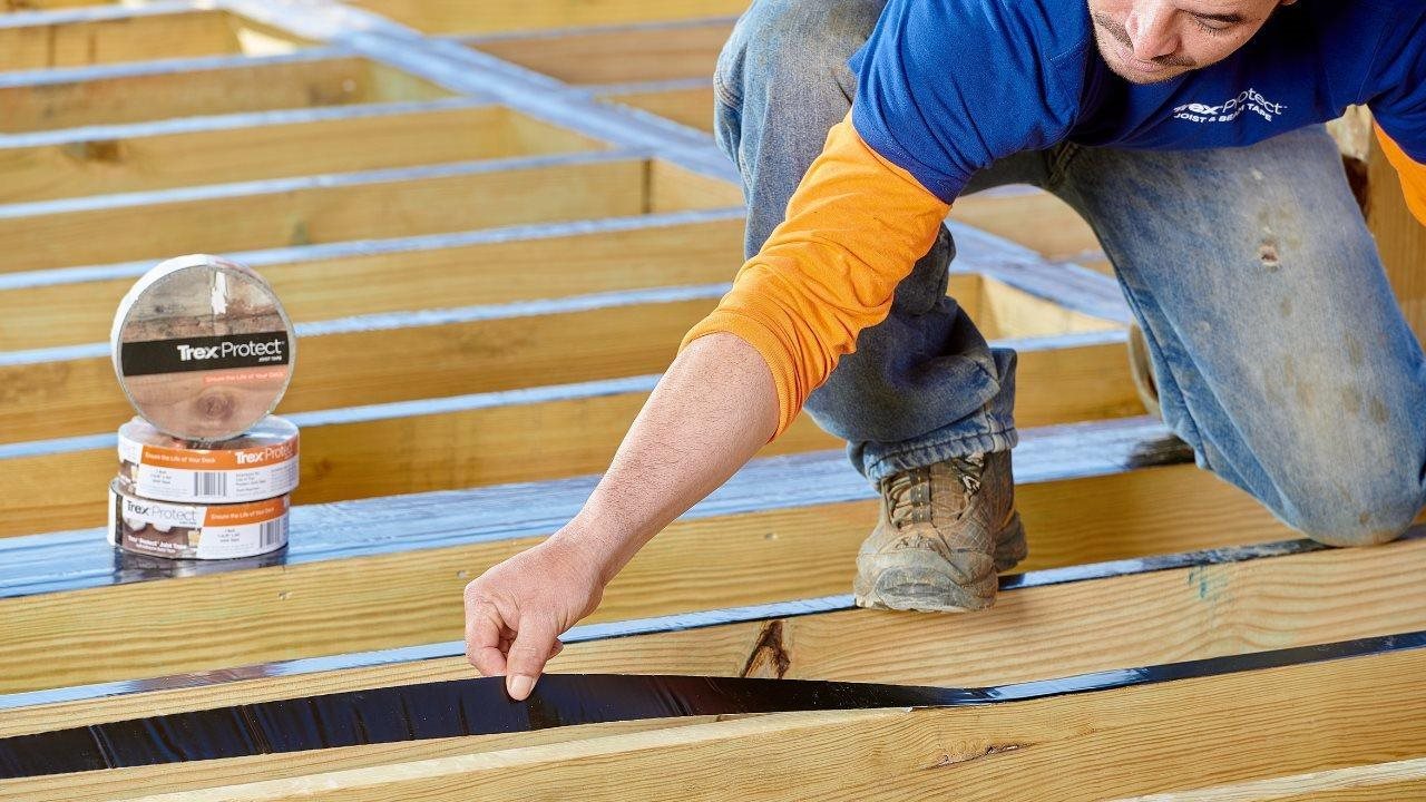 Man applying Trex® Protect joist flashing tape to his deck.