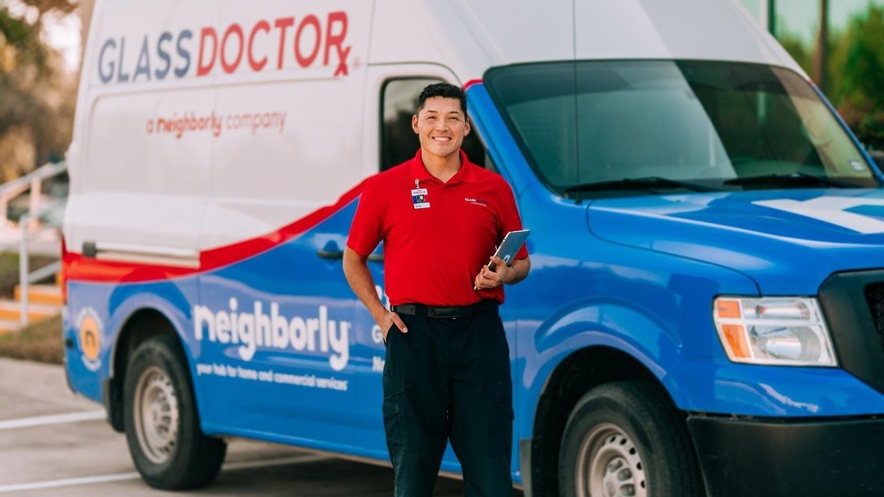 Smiling male representaive from Glass Doctor standing outside in front of his truck parked in a neighborhood.