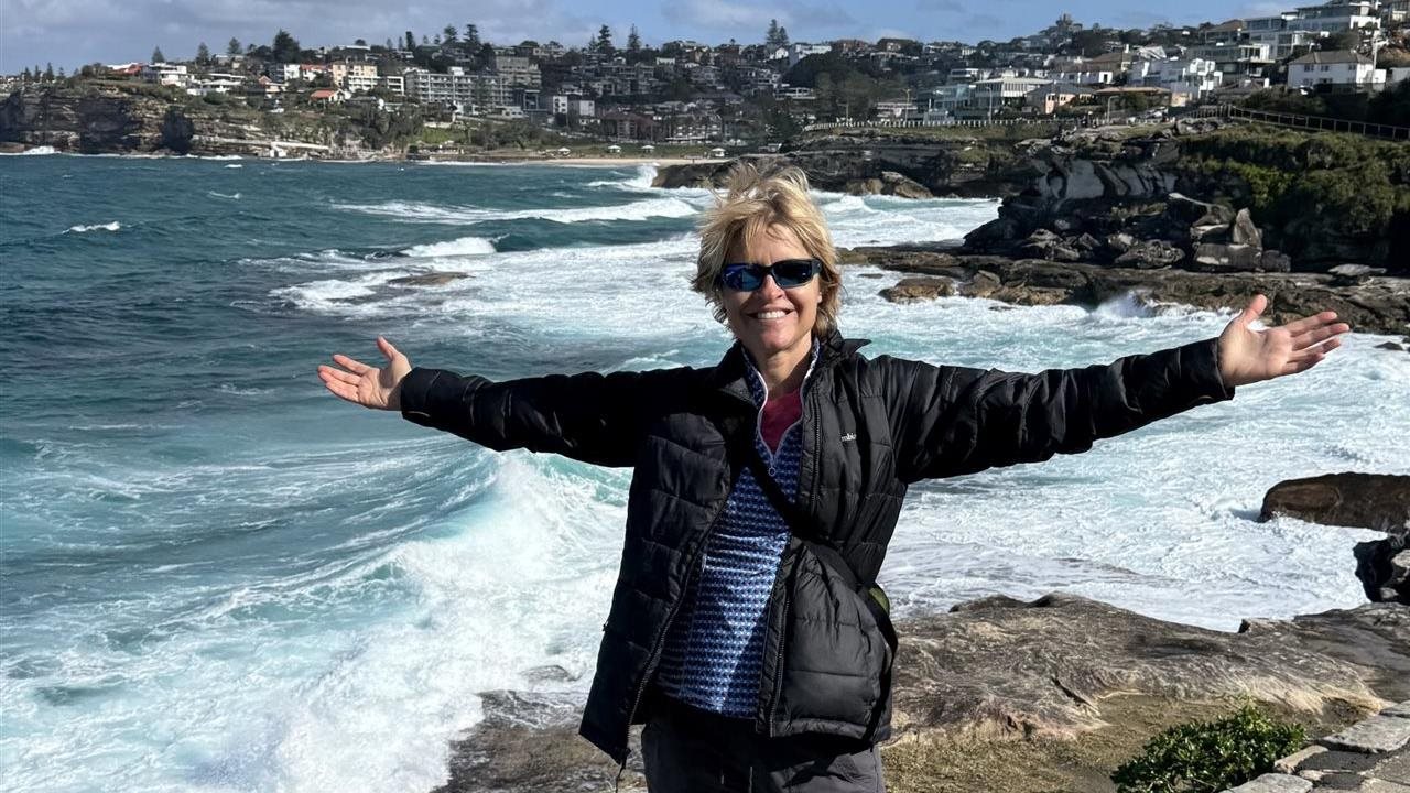 Sherri with outstretched arms standing on a coast line