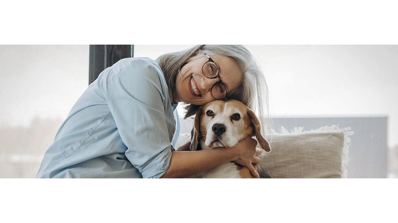 Senior woman hugging her beagle while relaxing at home.