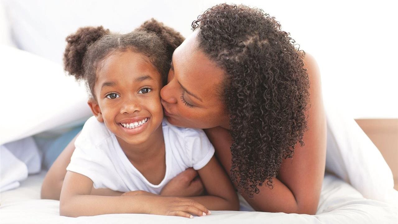 Mother kissing her daughter on the cheek. Rheem®'s Endeavor line are HVAC systems with variable-speed compressors.