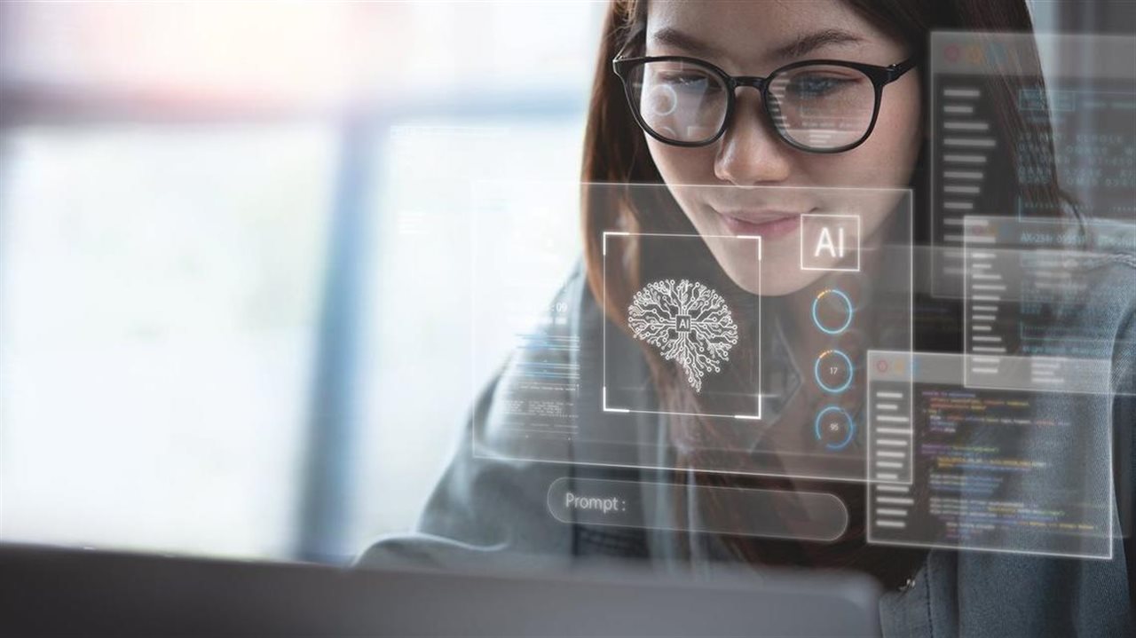 Young woman wearing glasses thinking about AI as she crafts her brand message using her laptop at work.
