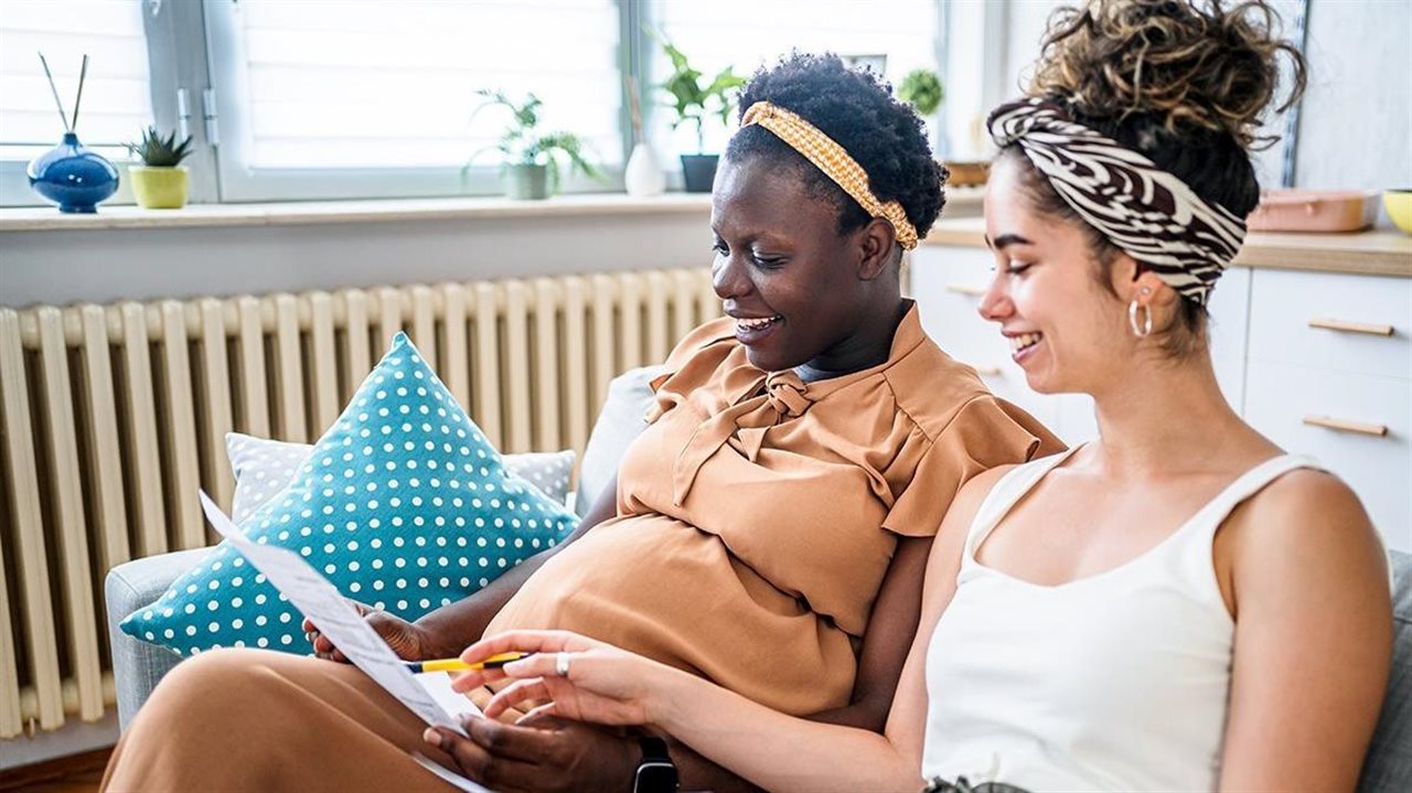 Two women wearing headbands smile as they rifle through health care documents.